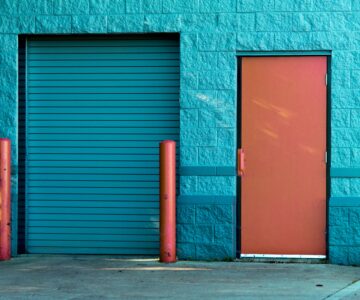 A blue wall and a blue garage door with a brown door next to it